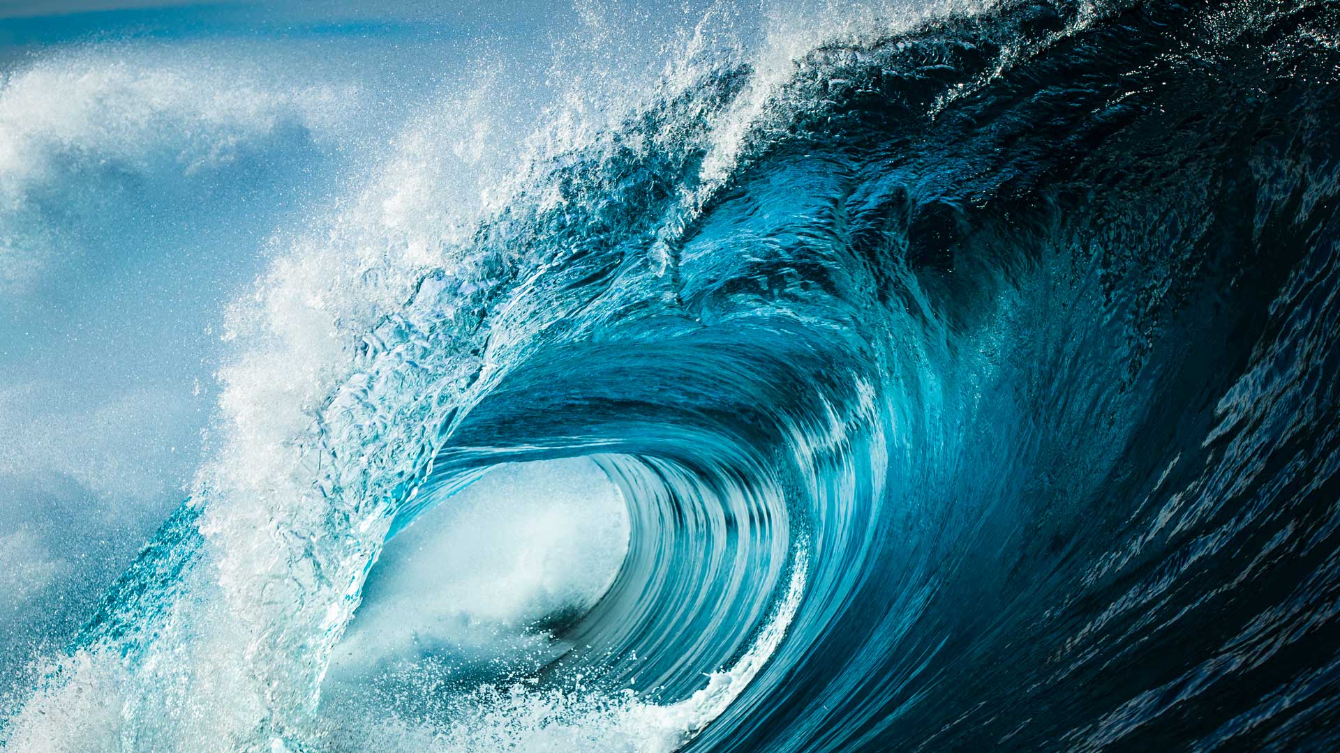 Close up detail of powerful teal blue wave breaking in open ocean on a bright sunny afternoon